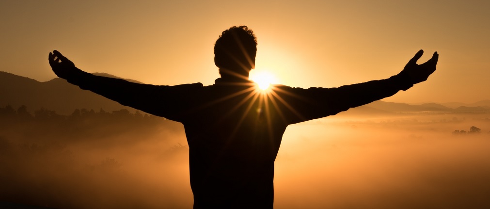 a man extending his arms toward the sunet